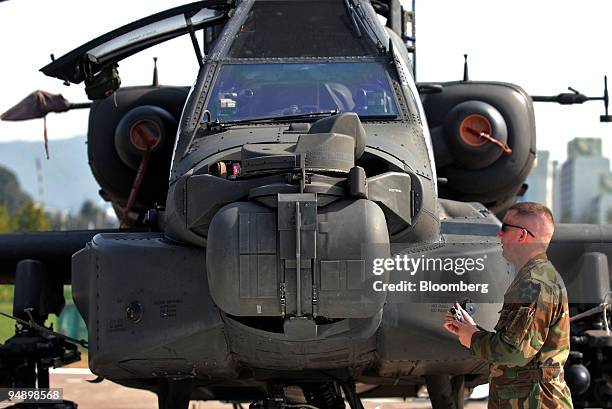 Soldier stands next to a Boeing AH-64D Longbow Apache attack helicopter on display as part of the 2005 Seoul Aerospace & Defense Exhibition in Seoul,...