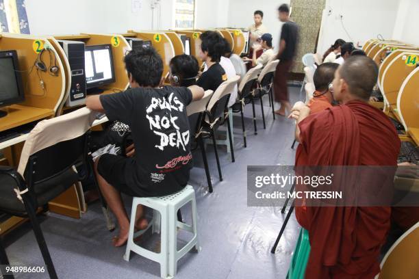 Buddhist monk looks at a teenager with a tee-shirt "Punks are not dead" in a cybercafe in Yangon, Myanmar, on June 10, 2009. Internet is very slow...