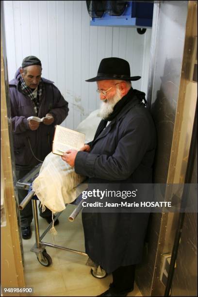 Deux membres de la Hevra Qadisha, les pompes funebres religieuses de Jerusalem recietnt des psaumes pres de la depouille de Ilan Halimi.