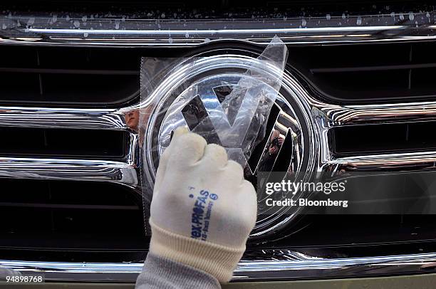 Worker places the logo of a Volkswagen Tiguan car on an automobile on the production line at the Volkswagen factory in Wolfsburg, Germany, on Friday,...