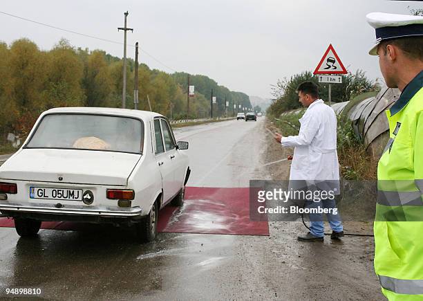 Transportation ministry officials spray disinfectant on the tires of passing cars outside the city of Galati, Romania, on Sunday, October 16, 2005....