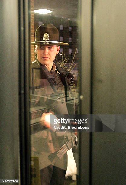 An Illinois State Police officer with an M-16 stands guard inside Neptune Hall, across from Cole Hall, on the campus of Northern Illinois University...