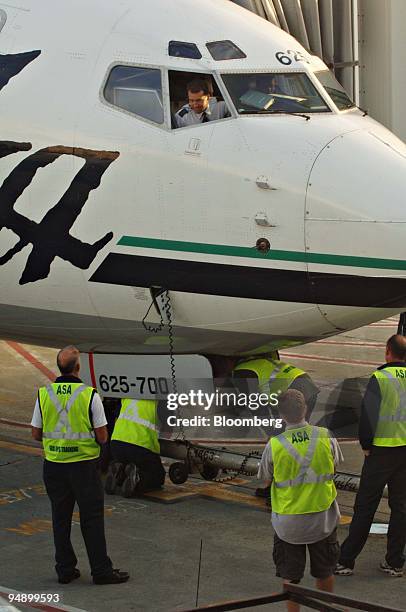 An Alaska Airlines pilot talks to ground crew from the cockpit of a jet sitting at a gate at Ted Stevens International Airport in Anchorage, Alaska,...