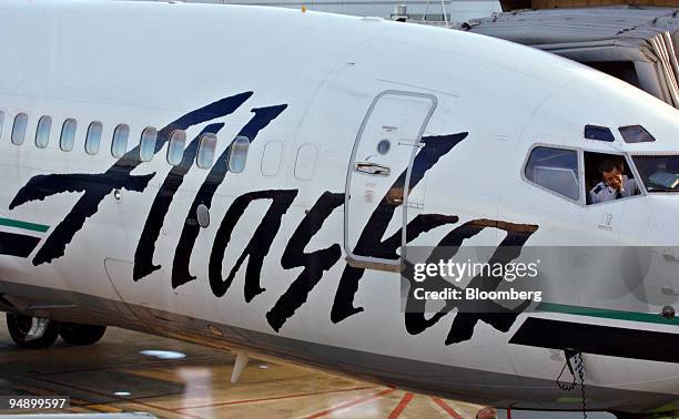 An Alaska Airlines pilot talks to ground crew from the cockpit of a jet sitting at a gate at Ted Stevens International Airport in Anchorage, Alaska,...