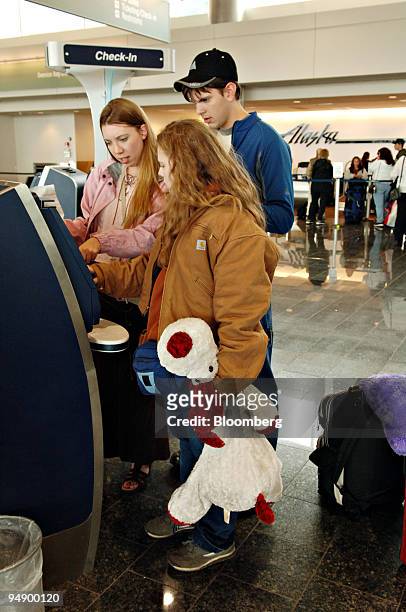 Alaska Airlines passenger Laura Visscher, center, checks in at a self service kiosk with friends Annette, left, and Ben Fosgaten in Ted Stevens...
