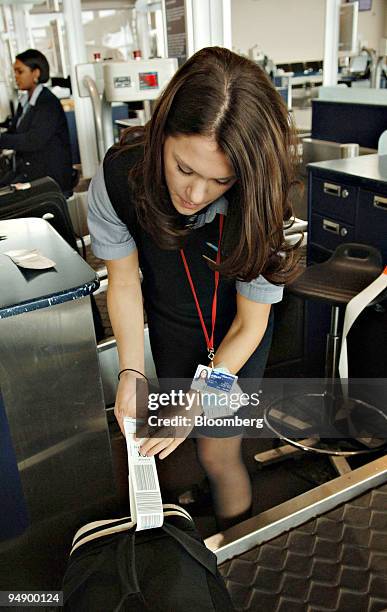 Alaska Airlines customer service representative Jubilee Brost tags a customers bag as she checks passengers in at Ted Stevens International Airport...