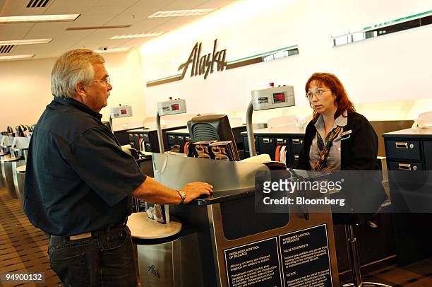 Ron Campbell checks the details of his flight with customer service representative Cathy Kracker at an Alaska Airlines ticket counter at Ted Stevens...