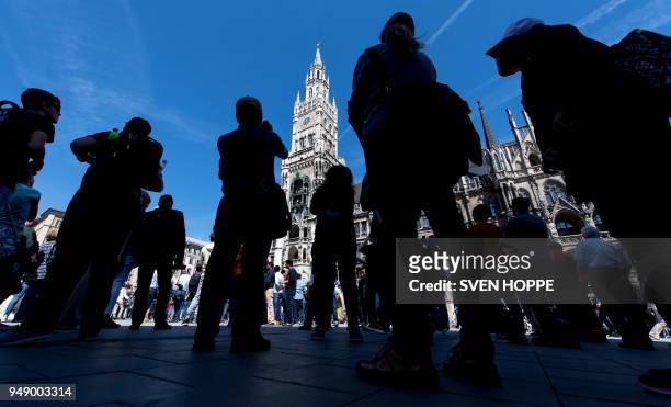 People wait for the Glockenspiel clock tower to mark 12am at the Marienplatz in Munich, southern Germany. - The Rathaus-Glockenspiel of Munich, with...