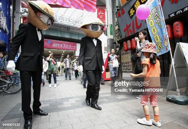 Performance group 'Medaman-Medaman' or 'Eyeball Man', street performer covered with the mask of the big eyeball parades around a shopping district in...