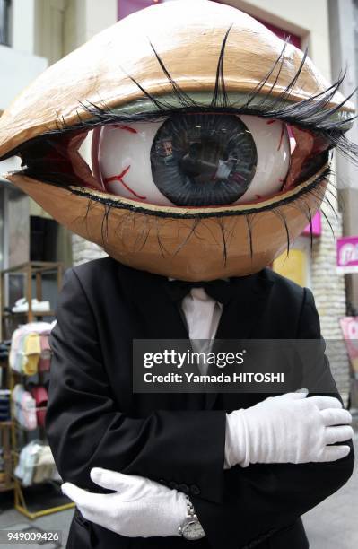 Performance group 'Medaman-Medaman' or 'Eyeball Man', street performer covered with the mask of the big eyeball parades around a shopping district in...