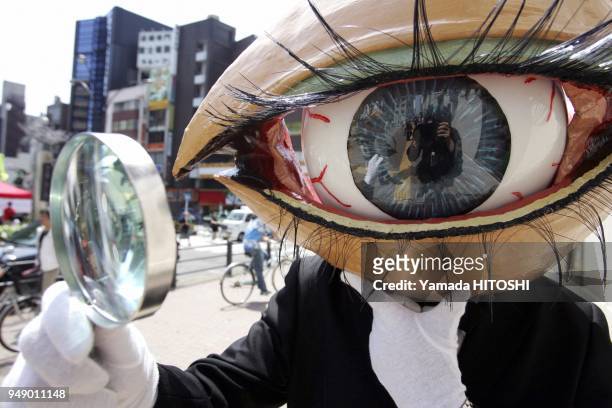Performance group 'Medaman-Medaman' or 'Eyeball Man', street performer covered with the mask of the big eyeball parades around a shopping district in...
