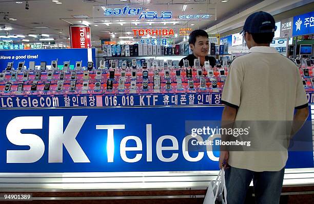 Sales clerk offers SK Telecom Co. Cell phones at an electronics shop in Seoul, South Korea Thursday, July 29, 2004.