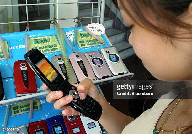 Customer looks at a selection of NEC cell phones at a store in Tokyo Tuesday, July 27, 2004. NEC Electronics Corp., Japan's third-biggest chipmaker,...