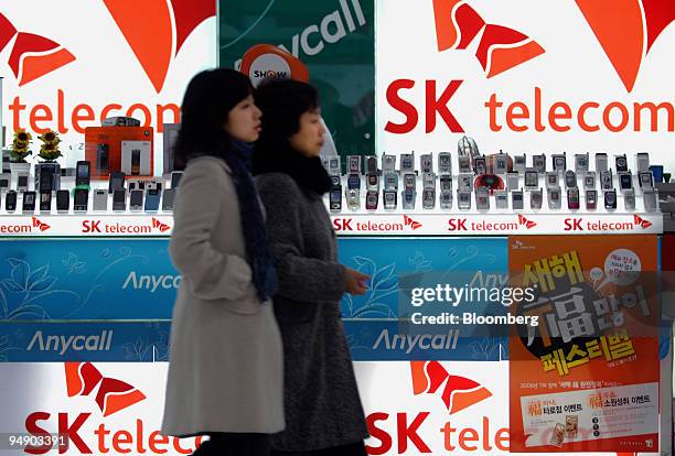 Customers walk past the SK Telecom Co. Booth at an electronics shop in Seoul, South Korea, on Wednesday, Jan. 30, 2008. SK Telecom Co., South Korea's...