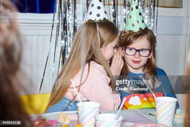 portrait of two girls having fun at a party - child whispering stockfoto's en -beelden