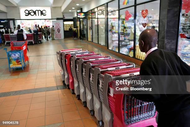 An employee handles shopping trolleys outside a Game supermarket in the Manda Hill mall in Lusaka, Zambia, on Friday, Feb. 1, 2008. About 68 percent...