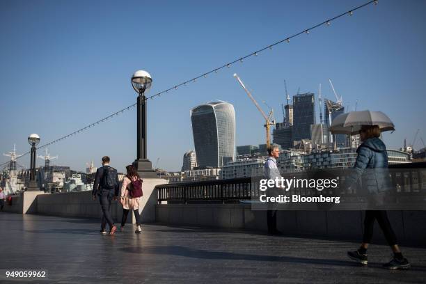 Pedestrians walk along the River Thames in view of 20 Fenchurch Street, also known as the 'Walkie-Talkie' in London, U.K., on Friday, April 20, 2018....