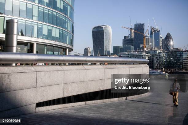 Pedestrians pass through the More London office space in view of 20 Fenchurch Street, also known as the 'Walkie-Talkie' and construction in the City...