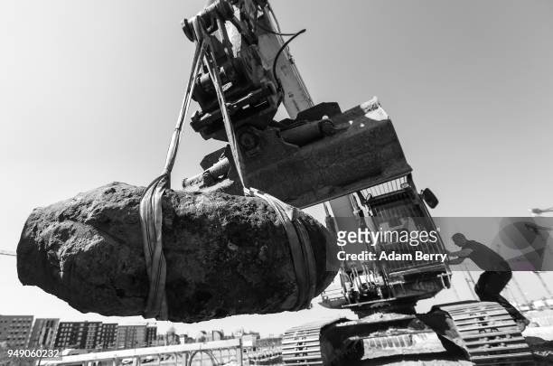 Bomb disposal technician uses a backhoe to remove an unexploded 500-kilogram bomb from World War II after its deactivation on April 20, 2018 in...