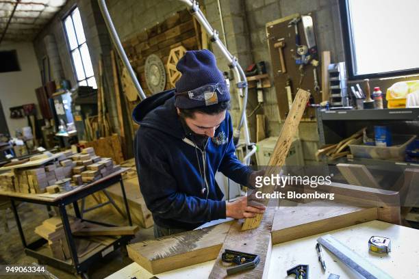 Worker attaches a support leg to a rustic table base at the Old Wood Co. Sustainable furniture manufacturing facility in Asheville, North Carolina,...
