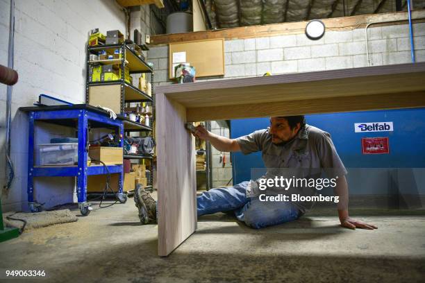 Worker brushes the wood of table to prepare it for finishing at the Old Wood Co. Sustainable furniture manufacturing facility in Asheville, North...