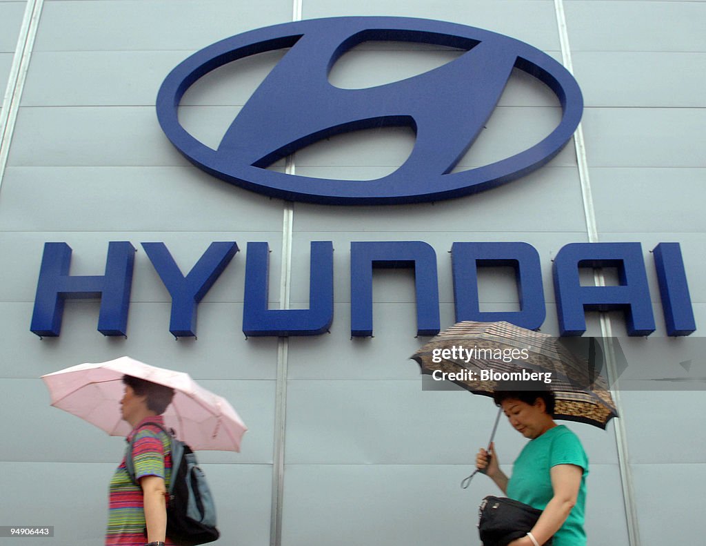 Pedestrians walk past a Hyundai Motor Co. advertising board