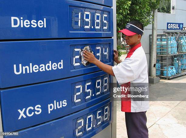 Filipino gasoline attendant at a Petron pumping station wipes a sign board showing the current prices of fuel in Manila Tuesday, July 6, 2004....