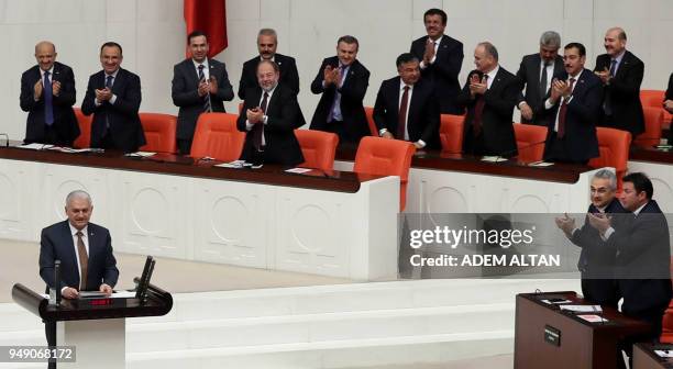Members of Parliament applaud as Turkish Prime Minister Binali Yildirim speaks during the debate motion on proposed early presidential and...