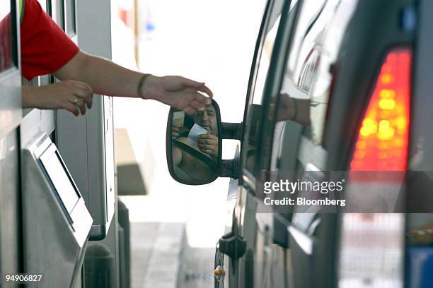 Motorist pays at a toll-booth on the R-4 motorway south of Madrid, Spain, Monday, July 5, 2004. Citigroup Inc., Merrill Lynch & Co., Santander...