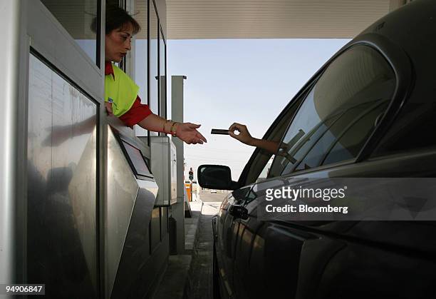 Motorist pays at a toll-booth on the R-4 motorway south of Madrid, Spain, Monday, July 5, 2004. Citigroup Inc., Merrill Lynch & Co., Santander...