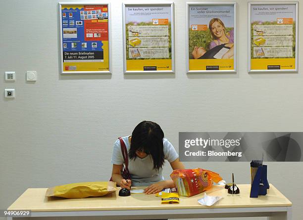 Customer fills out forms in a Deutsche Post branch in Frankfurt, Germany, Tuesday, July 26, 2005. Deutsche Post AG, Europe's biggest postal service,...