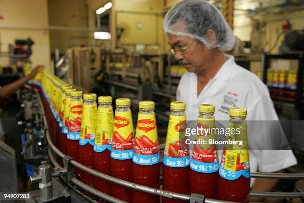Workers check the labels on bottles of Maggi sauce at the Nestle Malaysia plant in Selangor, Malaysia July 20, 2005.