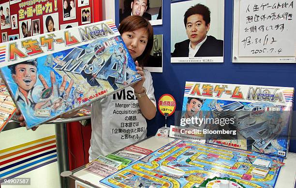 Takara Co. Employee shows off the company's 'The Game of Life M&A' at a toy show in Tokyo Thursday, July 21, 2005. Pictured above the game is a...