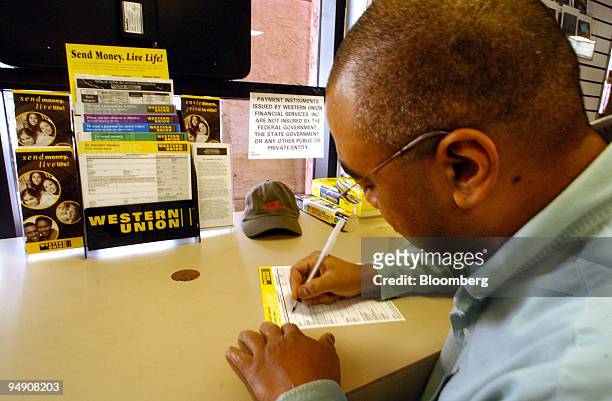 Daniel Salcedo fills out a form to wire money at a Western Union outlet in San Diego, California February 3, 2004. First Data Corp., parent of the...