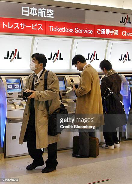 Passengers buy a tickets at a Japan Airlines Co. Ltd. Automatic ticketing machine at Haneda Airport in Tokyo Tuesday, February 3, 2004.