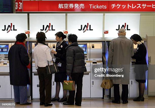 Passengers buy a tickets at a Japan Airlines Co. Ltd. Automatic ticketing machine at Haneda Airport in Tokyo Tuesday, February 3, 2004.