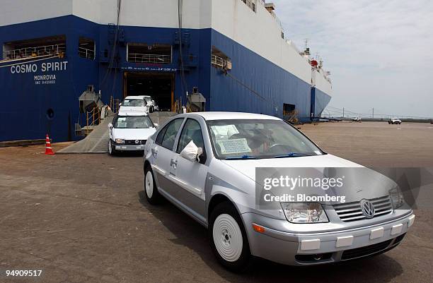 Volkswagen automobiles, partially covered in protective plastic, are driven off a ship at the port of Brunswick, Georgia, on Monday, June 14, 2004....