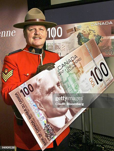 Sgt. H. Moshe Gordon, the Royal Canadian Mounted Police anti-counterfeiting coordinator in Ontario, holds a mockup of the newly-redesigned C$100 bill...
