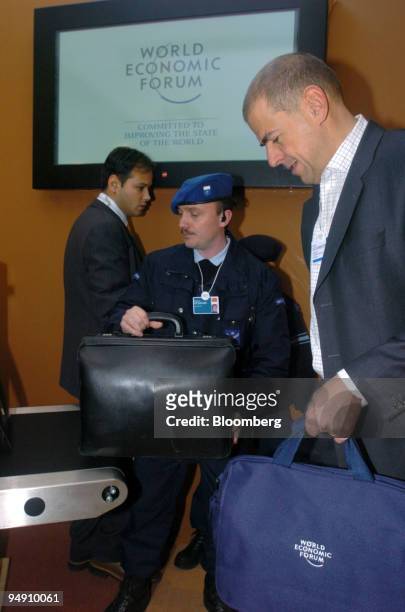 Ulrich Schumacher, president & CEO, Infineon Technologies, right, prepares to put his bag on the xray machine and go through security as he enters...