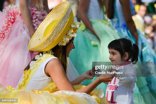 Young girl enjoys looking at the Dream Flowers by Isabel Borges - hostesses wearing a hand made floral dresses and hats in the center of Funchal, the...