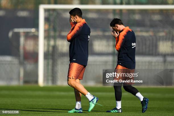 Luis Suarez and Lionel Messi of FC Barcelona walk onto the pitch at the start of a training session ahead of the Spanish Copa del Rey Final match at...