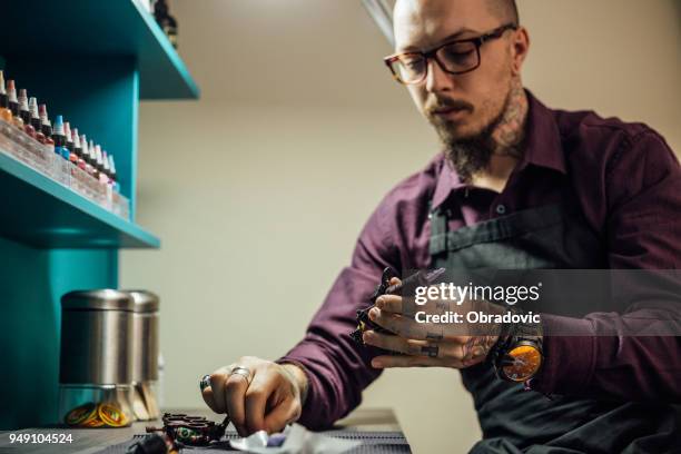 tattoo artist holding tattoo gun with needle attached - surgical suture stock pictures, royalty-free photos & images