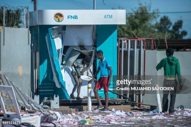 Children play around a vandalised ATM in North West Province on April 20 as protest continued for a second day in province capital of Mahikeng. -...