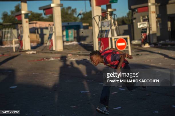 Looter runs for cover from South African police rubber bullets on April 20 as protest continued for a second day in in North West province capital of...