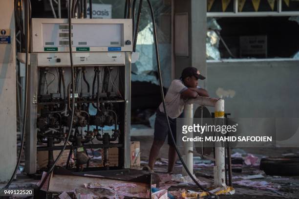 Boy stands by a petrol pump that was looted, on April 20 as protest continued for a second day in the South African North West province capital of...