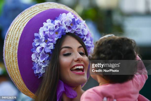 Young girl enjoys looking at the Dream Flowers by Isabel Borges - hostesses wearing a hand made floral dresses and hats in the center of Funchal, the...