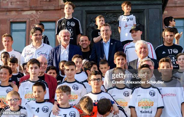 President Reinhard Grindel and Rudi Voeller pose with kids of Hanauer FC during the 125th anniversary of 1. Hanauer FC on April 20, 2018 in Hanau,...