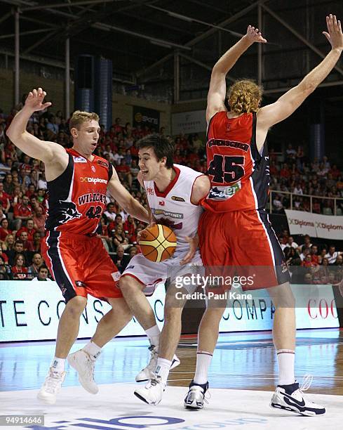 Brad Hill of the 36'ers attempts to get past Shawn Redhage and Luke Schenscher of the Wildcats during the round 13 NBL match between the Perth...