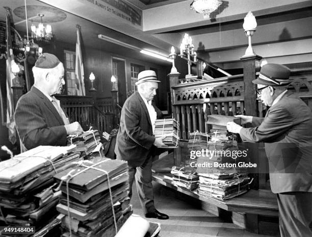 From left, Louis Dickstein, Ben Greenspan and Morton Sadwin help collect and pack old books in preparation for the relocation of the Congregation...
