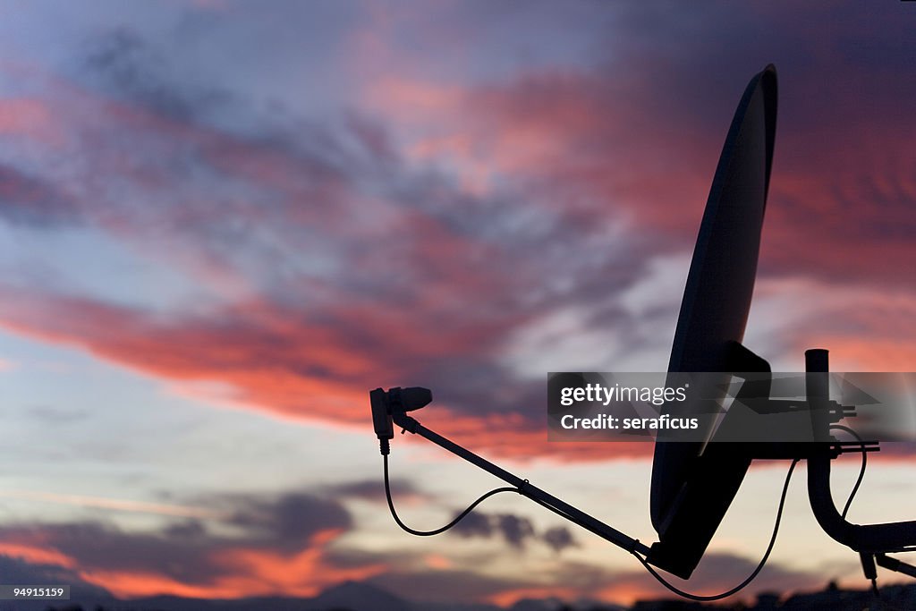 A satellite dish in front of a sunset sky 